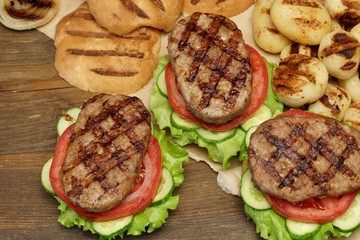 Picnic Table Top With BBQ Grilled Burgers And Vegetables
