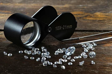 Rolgordijnen Diamanten geslepen met een vergrootglas op een rustieke houten ondergrond © Björn Wylezich