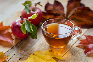 Glas heiße Tasse Tee auf einem Holztisch mit Herbstlaub und ap
