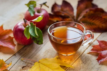 Door stickers Tea glass hot cup of tea on a wooden table with autumn leaves and ap