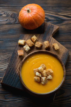 Pumpkin cream-soup, dark brown rustic wooden surface, above view