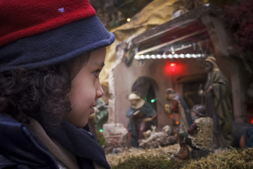 Niña mirando el escaparate de una tienda en navidad. Tiendas en navidad. Niña con gorro y bufanda. Campaña de navidad. 