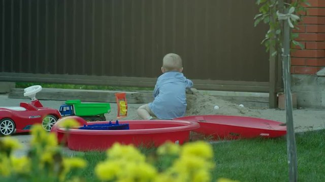 Boy Playing with Car in a Sandpit