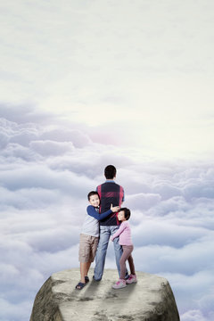 Kids and dad standing on the cliff © Creativa Images