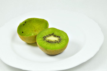 Halved Kiwi Fruits / halved kiwi fruits, full and empty, on white plate, close up, macro, horizontal