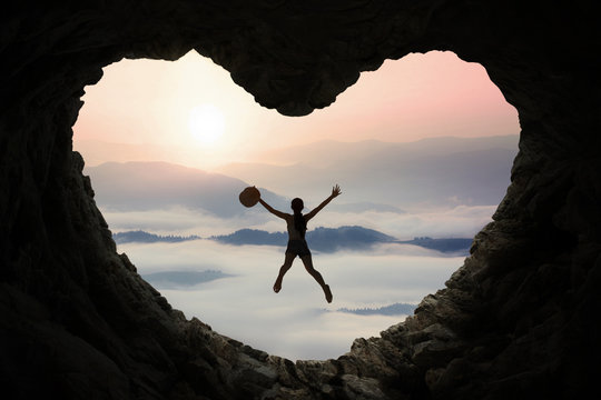 Woman leaps inside cave at mountain - Powered by Adobe