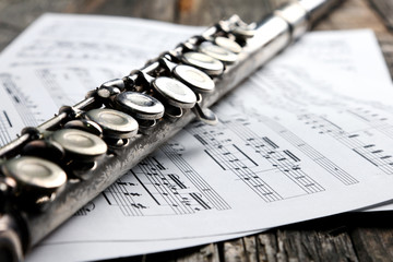 Old silver flute and music notes on rusty table