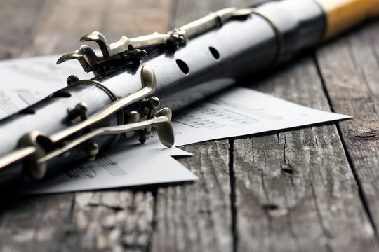 Old black flute and music notes on rusty wooden table