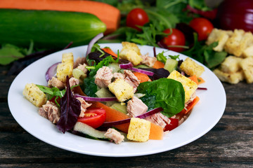 Tuna salad with Spinach, rocket, red ruby chard, tomatoes, cucumbers, white cheese, carrot, red onion, croutons on old blue stone background