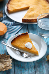Tasty pumpkin pie on plate on a blue wooden table