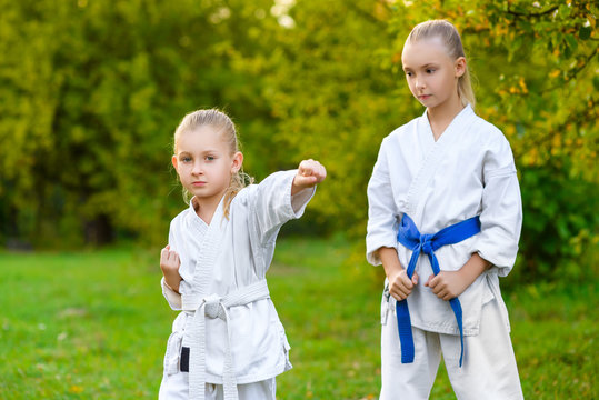 girls in white kimono during training karate exercises at summer - Powered by Adobe