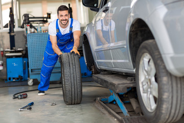 mechanic hands in blue uniform pushing a black tyre