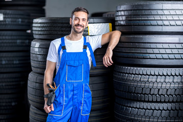 mechanic with car tires - obrazy, fototapety, plakaty