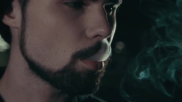 young handsome bearded man smoking cigarette 