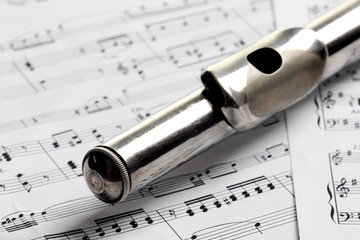 Old rusty silver flute on music notes