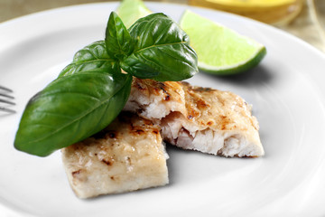 Dish of fish fillet with basil and lime on plate close up