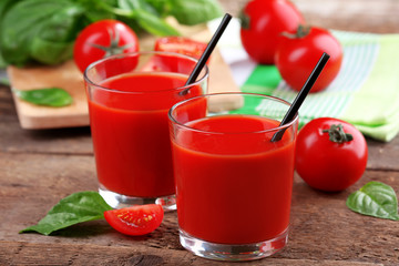 Glasses of tomato juice on wooden table, closeup