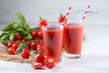 Glasses of tomato juice with vegetables on wooden table close up
