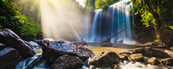 Tropical waterfall in jungle with sun rays
