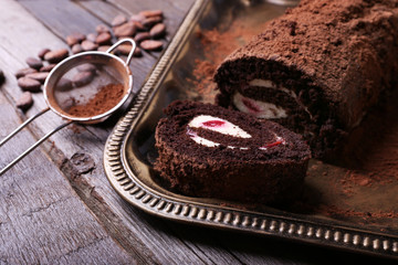 Chocolate roll with cream and berries on table close up