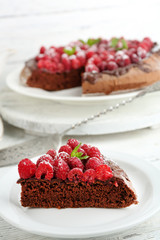 Piece of cake with chocolate Glaze and raspberries on color wooden background
