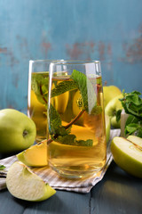 Glasses of apple juice with fruits and fresh mint on table close up