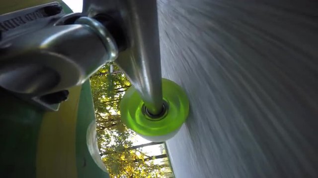 POV of longboard wheels rolling in the sunny city park