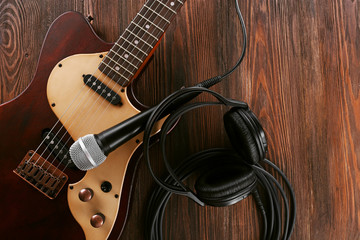 Fototapeta premium Electric guitar with microphone and headphones on wooden table close up