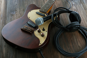 Naklejka premium Electric guitar with microphone and headphones on wooden table close up