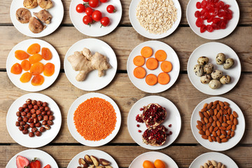 Different products on saucers on wooden table, top view