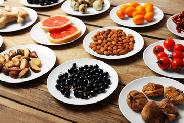 Different products on saucers on wooden table close up