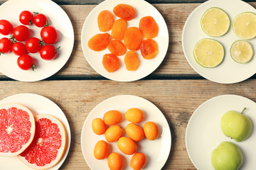 Different products on saucers on wooden table, top view