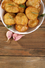 Delicious baked potato with rosemary in bowl on table close up