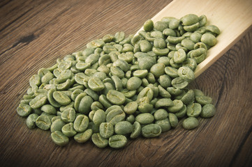 Spoon with green coffee beans on the wood