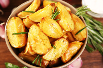 Baked potato wedges on wooden table, closeup
