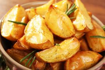 Baked potato wedges on wooden table, closeup