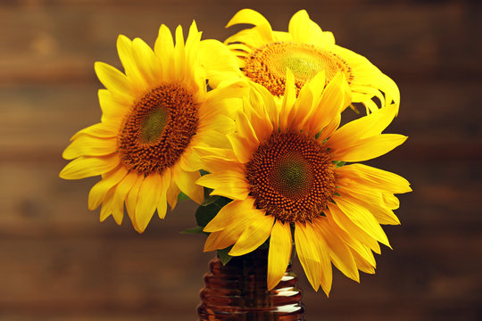 Beautiful bright sunflowers in vase on wooden background