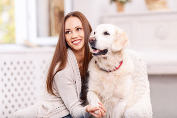 Lovely girl is smiling vividly while caressing a dog.