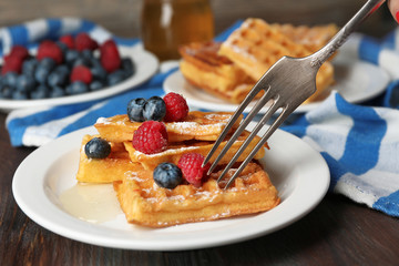 Sweet homemade waffles with forest berries and sauce on table background