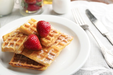 Sweet homemade waffles with strawberries  on plate, on table background
