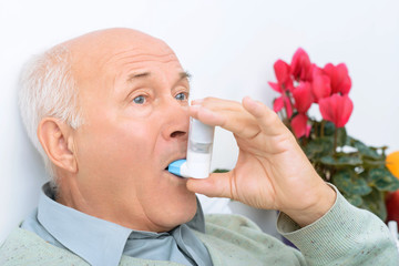  Senior aged man uses inhaler to cure his ache.