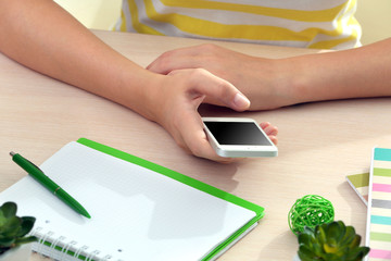Woman using mobile phone on workplace close up