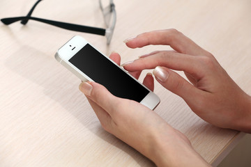 Woman using mobile phone on workplace close up