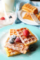 Sweet homemade waffles with forest berries on plate, on light background