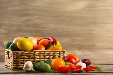 Heap of fresh fruits and vegetables in basket on wooden table close up