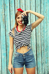 Beautiful girl with pretty smile and camera on color wooden background