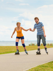 Obraz premium Young couple on roller skates riding outdoors