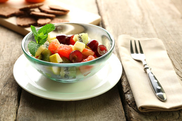 Fruit salad in glass bowl, on  wooden background