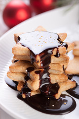 Christmas cookies with chocolate syrup and sugar balls on a white plate.