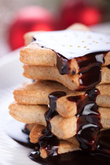 Christmas cookies with chocolate syrup and sugar balls on a white plate.